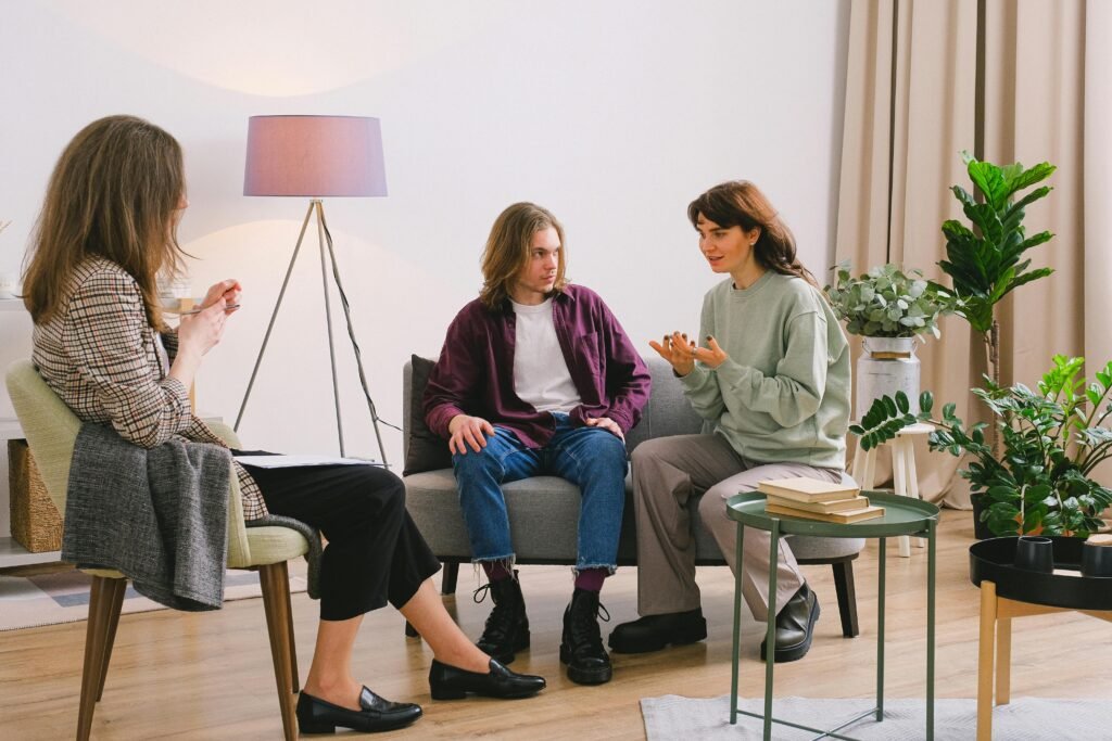 A psychologist consults a young couple in a bright living room setting.