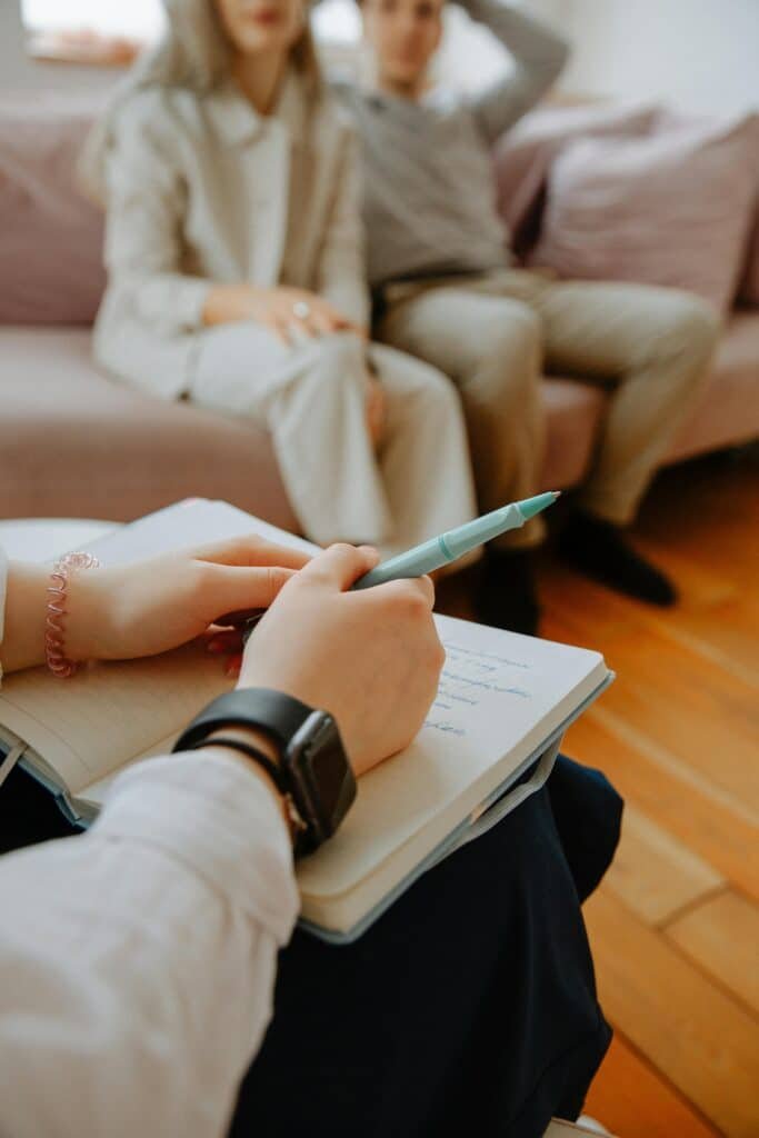 pexels-photo-3958385-3958385 A therapist takes notes while counseling a couple in an indoor session.